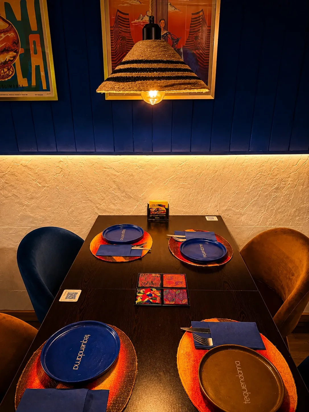 Mesa puesta con platos Tequendama bajo una lámpara de sombrero vueltiao